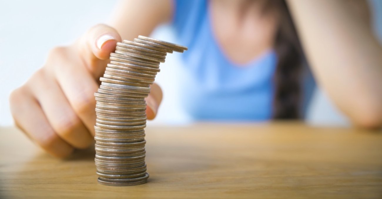 Eine Frau tippt mit dem rechten Zeigefinger gegen einen Stapel Münzen © iStock/Sezeryadigar Eine Frau tippt mit dem rechten Zeigefinger gegen einen Stapel Münzen © iStock/Sezeryadigar