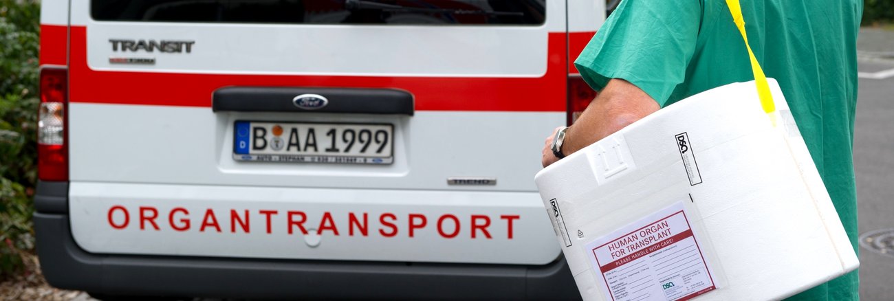 Ein Mann in OP-Bekleidung trägt eine Kühlbox für Organspenden zu einem Transporter mit der Aufschrift Organstransport © dpa/Soeren Stache Ein Mann in OP-Bekleidung trägt eine Kühlbox für Organspenden zu einem Transporter mit der Aufschrift Organstransport © dpa/Soeren Stache