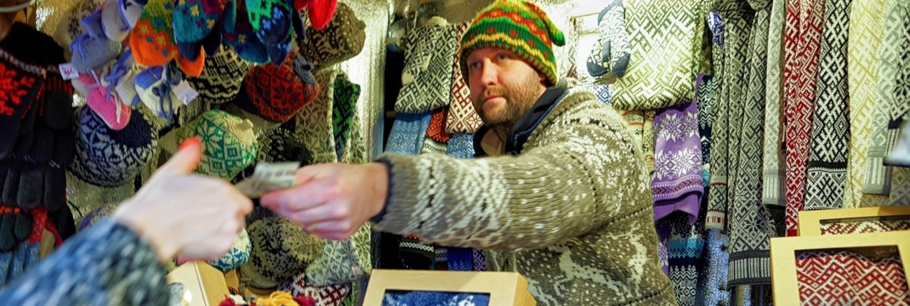 Marktverkäufer mit Strickwaren reicht einer Frau einen Euro-Schein © iStockphoto.com/Roman Babakin Marktverkäufer mit Strickwaren reicht einer Frau einen Euro-Schein © iStockphoto.com/Roman Babakin