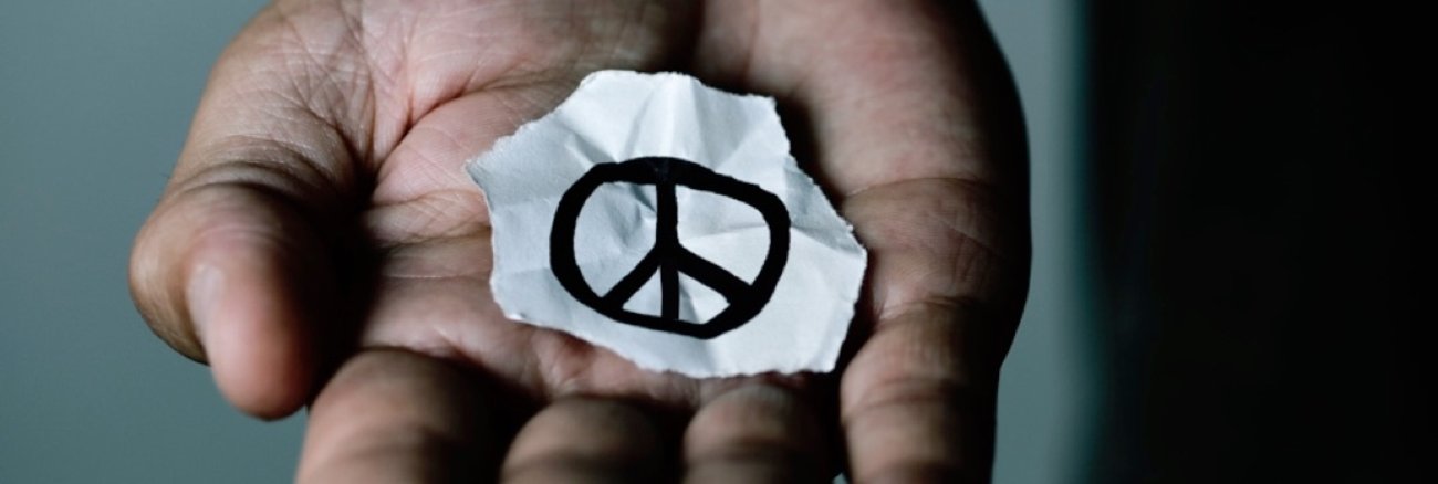 Das CND-Friedenssymbol auf einem abgerissenen Papier in einer aufgehaltenen Hand © iStockphoto.com/nito100 Das CND-Friedenssymbol auf einem abgerissenen Papier in einer aufgehaltenen Hand © iStockphoto.com/nito100