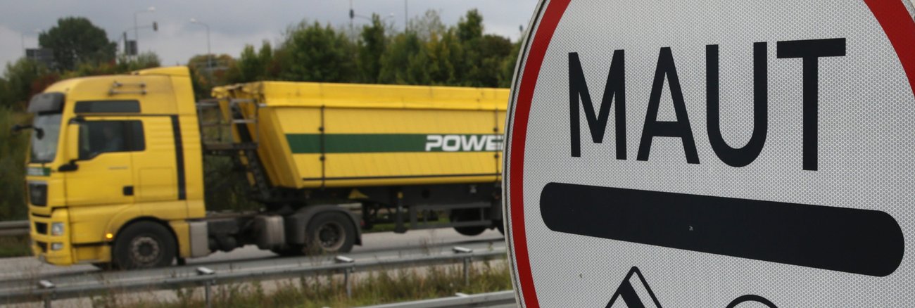 Ein gelber LKW fährt an einem Maut-Schild vorbei © Bernd Wüstneck/dpa