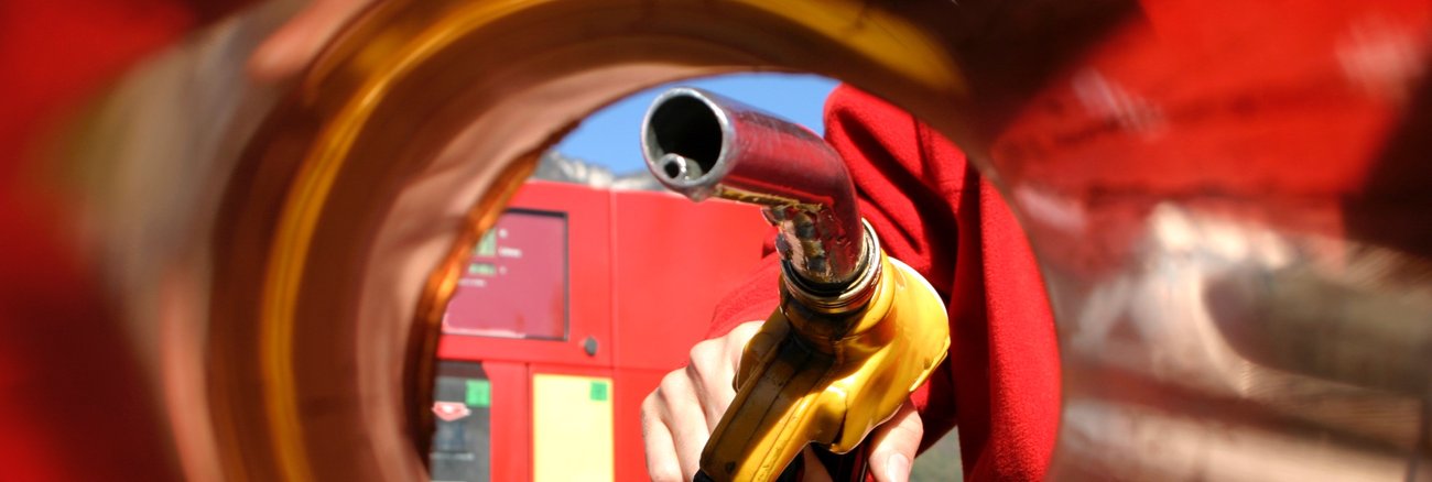 Zapfpistole in einer Hand aus dem Inneres eines Tanks fotografiert © iStock/Brasil2