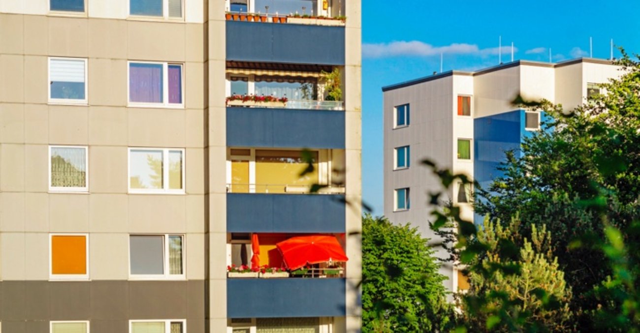 Mehrfamilienhäuser im Plattenbau-Stil mit einem roten Sonnenschirm auf einem Balkon © iStock/deepblue4you Mehrfamilienhäuser im Plattenbau-Stil mit einem roten Sonnenschirm auf einem Balkon © iStock/deepblue4you