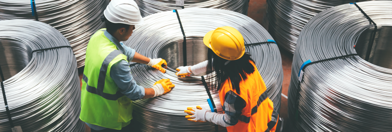 Eine Arbeiterin und ein Arbeiter in verpacken riesige Draht-Rollen © iStock/serts Eine Arbeiterin und ein Arbeiter in verpacken riesige Draht-Rollen © iStock/serts