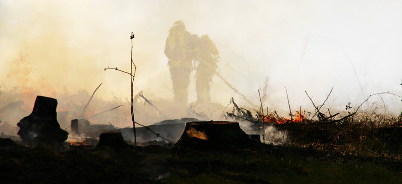 Zwei Feuerwehrleute bei Löscharbeiten in den Rauchschwaden eines Waldbrandes. Foto: Flickr.com/free-skier (CC BY-NC-SA 2.0)