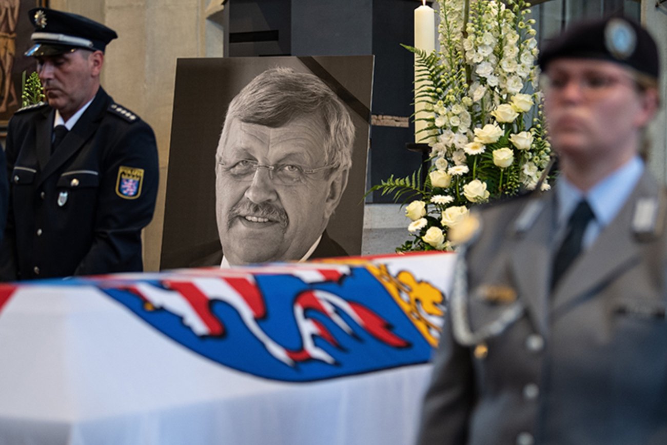 Das Konterfei von Walter Lübcke (CDU) ist hinter einem Bundeswehrsoldaten am Sarg bei einem Trauergottesdienst in der Martinskirche zu sehen. | Foto: © picture alliance/dpa/dpa-POOL/ Swen Pförtner