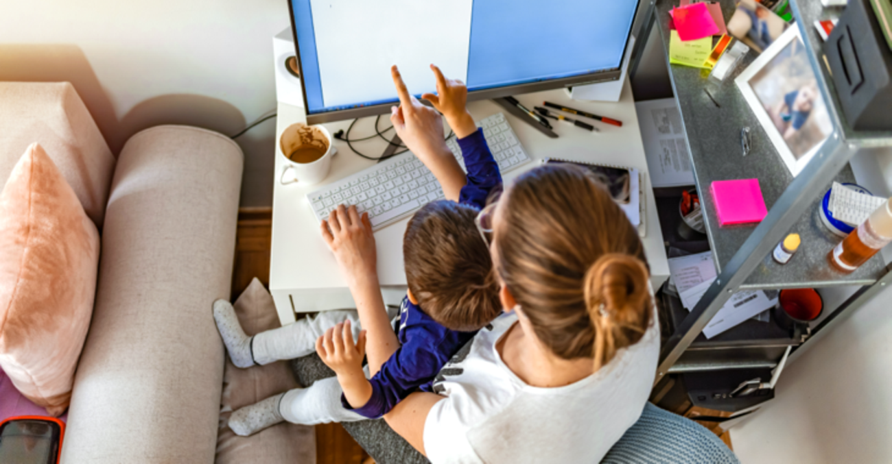 Eine Frau mit einem Kind auf dem Schoß zeigt auf einen Computerbildschirm © iStock/ljubaphoto Eine Frau mit einem Kind auf dem Schoß zeigt auf einen Computerbildschirm © iStock/ljubaphoto