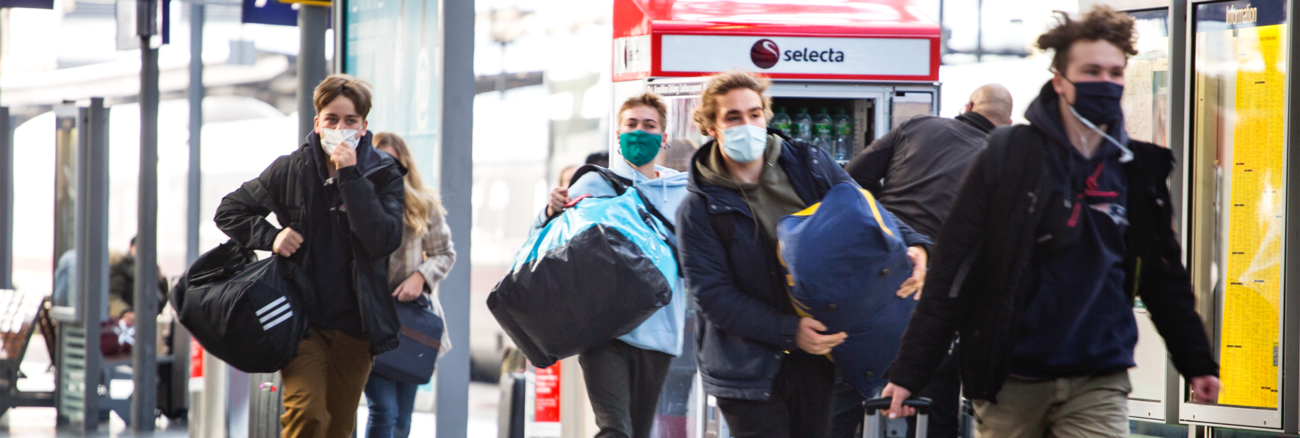 Vier junge Menschen mit Masken und Gepäck auf einem Bahnsteig im Hauptbahnhof Frankfurt am Main © iStock/ollo