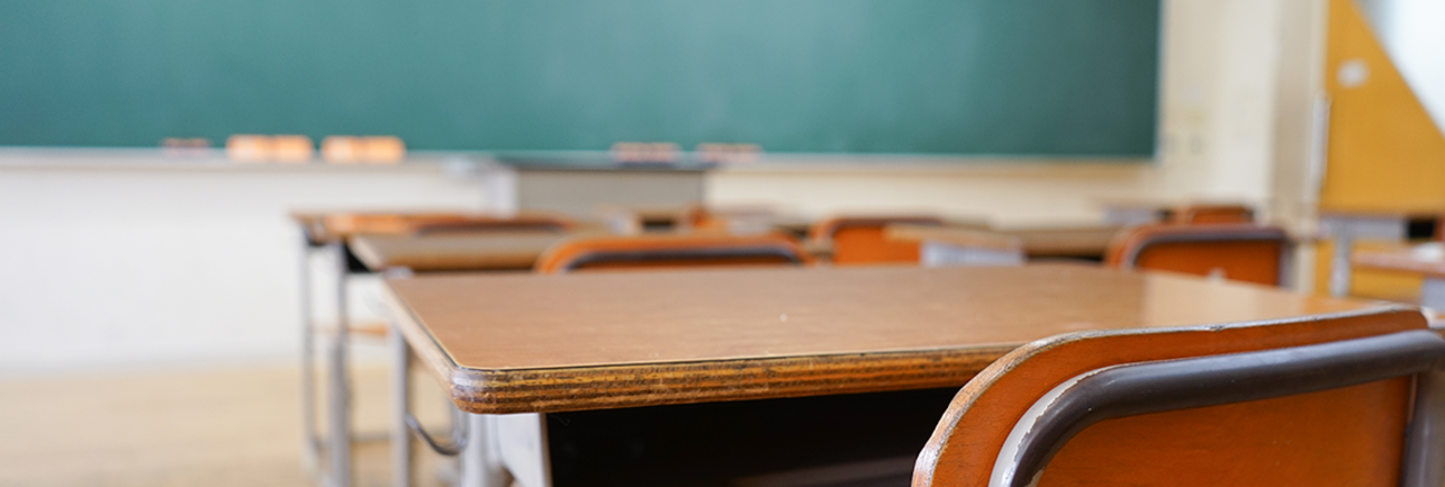 Ein leerer Klassenraum einer Schule mit einer sauberen Tafel, Pulten und abgenutzten Stühlen. Foto: © istock.com/maroke 