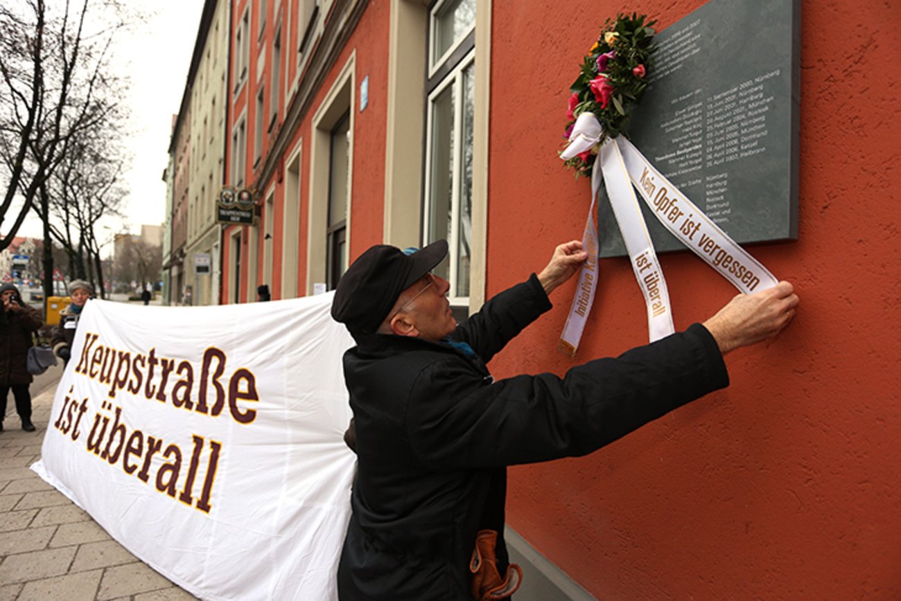 Mitat Özdemir, Mitglied einer Delegation der Kölner Initiative "Keupstraße ist überall", befestigt in der Trappentreustraße im Münchner Westend einen Trauerkranz an der Gedenktafel für das griechischstämmige NSU-Opfer Theodoros Boulgarides. | Foto: © picture alliance / SZ Photo