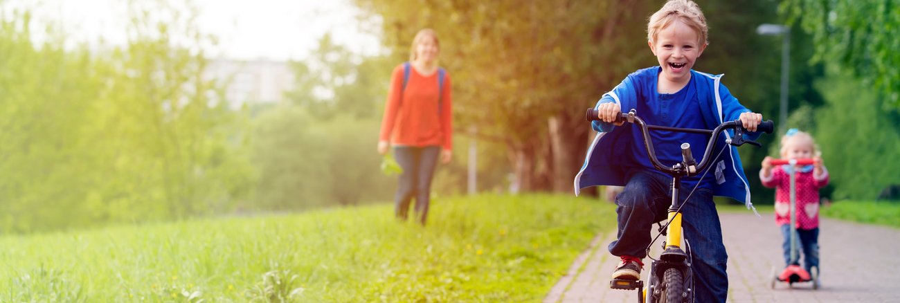 Eine Mutter mit ihrem Sohn auf einem Fahrrad und ihrer Tochter auf einem Tretroller © iStockphoto.com/Nadezhda1906 Eine Mutter mit ihrem Sohn auf einem Fahrrad und ihrer Tochter auf einem Tretroller © iStockphoto.com/Nadezhda1906