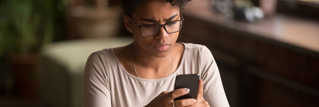 Junge Frau guckt besorgt auf ein Handy Junge Frau guckt besorgt auf ein Handy